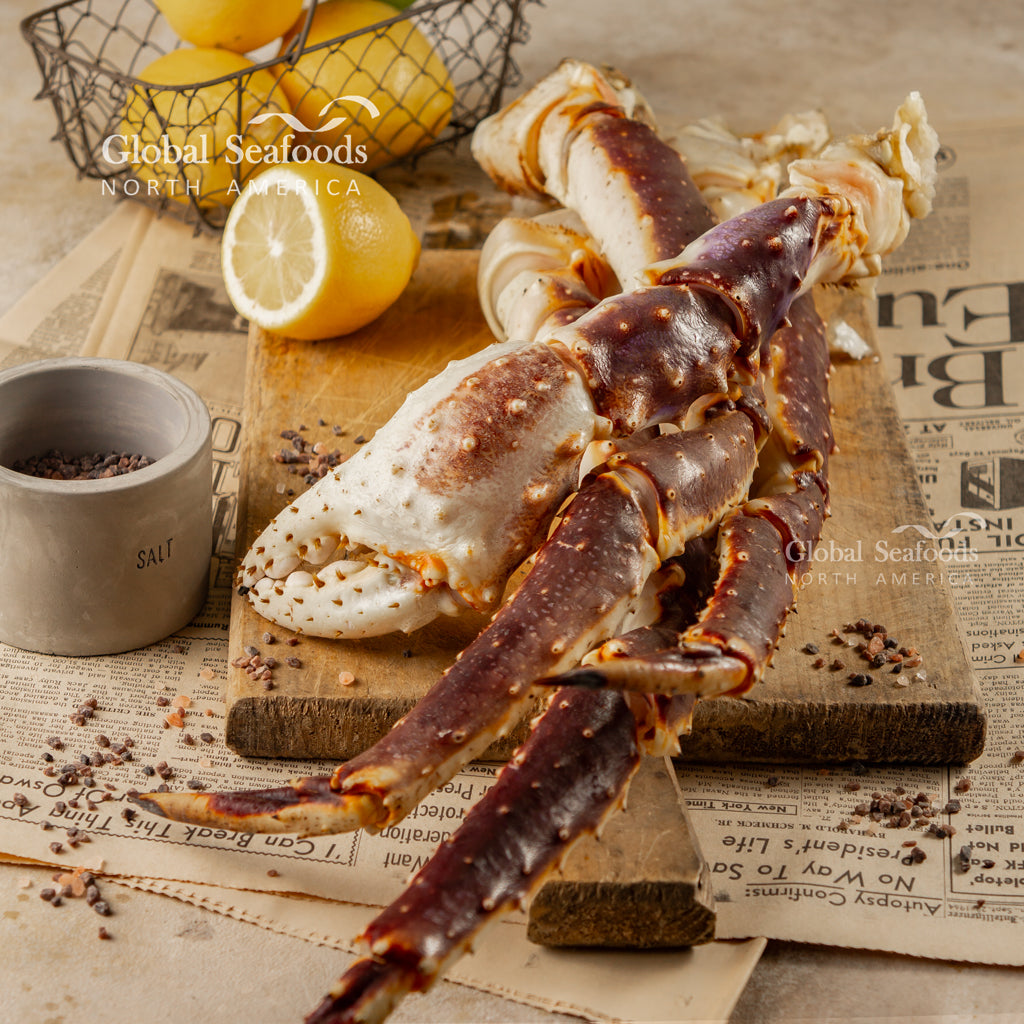 Uncooked King Crab legs placed on a wooden cutting board with lemon wedges, prepared for gourmet seafood cooking